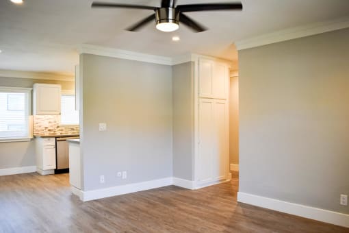 View from front entry of apartment featuring wood look flooring, partial view of kitchen with white cabinets, tile back splash.
