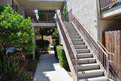 A staircase with a metal railing leads up to a balcony.
