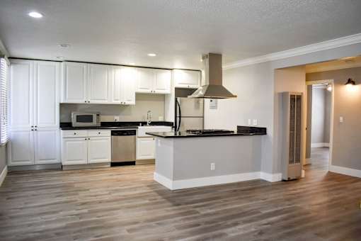 A modern kitchen with white cabinets and a wooden floor.