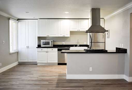 A kitchen with white cabinets and a black countertop.
