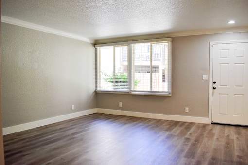 Empty room with a white door and a window with blinds.