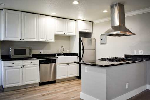 A kitchen with white cabinets and black countertops.