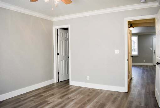 A room with a white door and a ceiling fan.