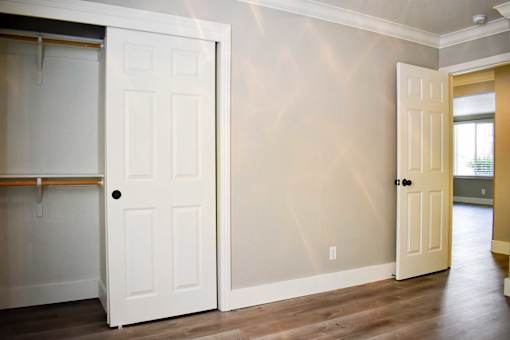 A white door is open to a room with wooden floors.