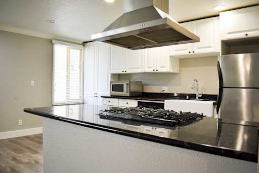 A modern kitchen with a stainless steel refrigerator and a black countertop.