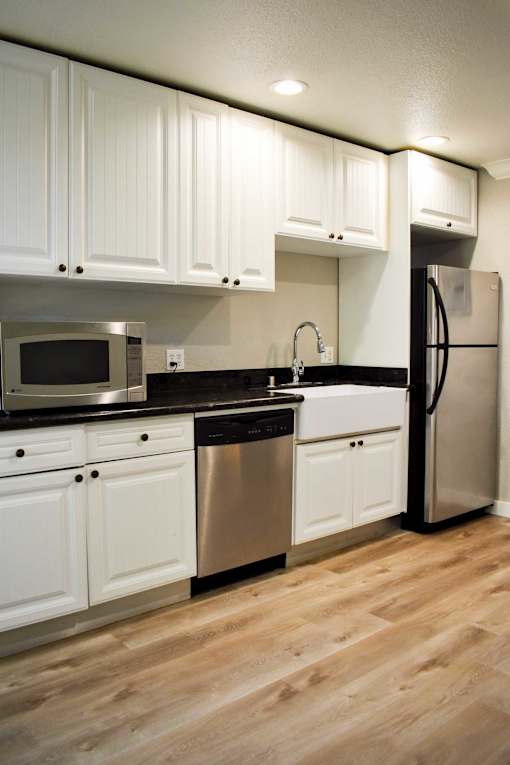 A kitchen with white cabinets and a black countertop.