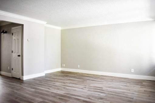 A room with a white door and wooden flooring.