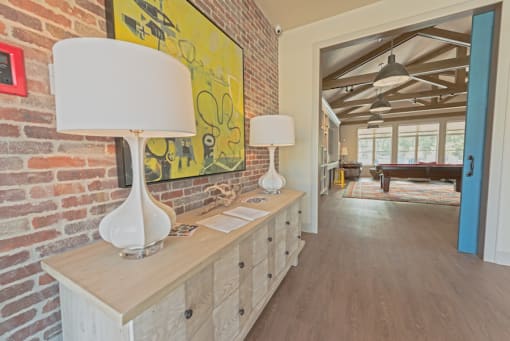 the living room of a house with a brick wall and a long table with lamps at Midtown Sam Houston Apartments, Texas, 77340
