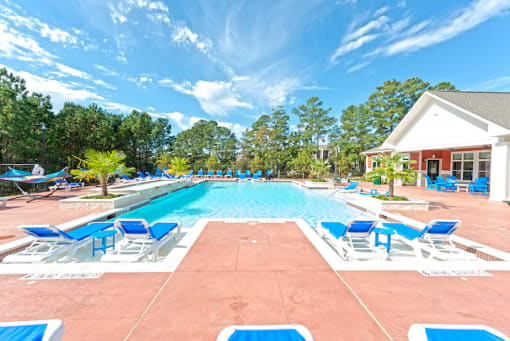 a swimming pool with blue and white chairs and a house at Midtown Sam Houston Apartments, Huntsville, TX, 77340