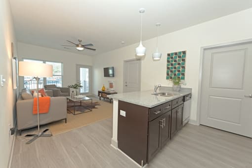 a living room with a kitchen and a couch at Midtown Sam Houston Apartments, Huntsville, Texas