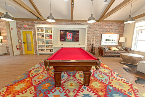 a red pool table in a living room with a brick wall at Midtown Sam Houston Apartments, Texas