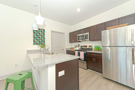 a kitchen with stainless steel appliances and a granite counter top at Midtown Sam Houston Apartments, Huntsville, TX