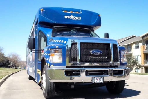 a blue bus parked on the side of a street at Midtown Sam Houston Apartments, Texas