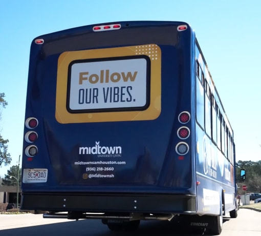 the back of a bus with a follow our vibes sign on it at Midtown Sam Houston Apartments, Texas, 77340