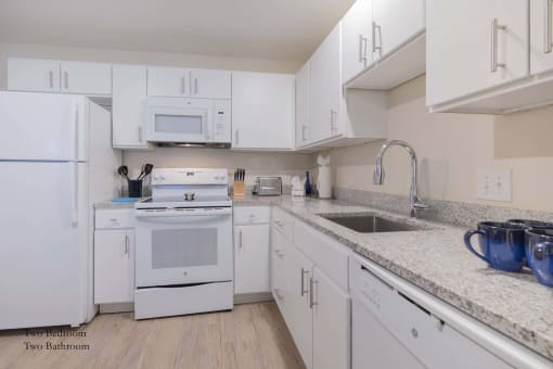 a white kitchen with white appliances and white cabinets at Parks Residential - Richardson, Richardson, Texas