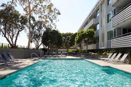 A swimming pool surrounded by lounge chairs and trees.