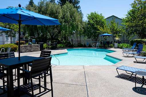 A pool area with chairs and umbrellas.