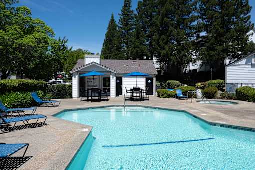 A pool with a blue umbrella and chairs.
