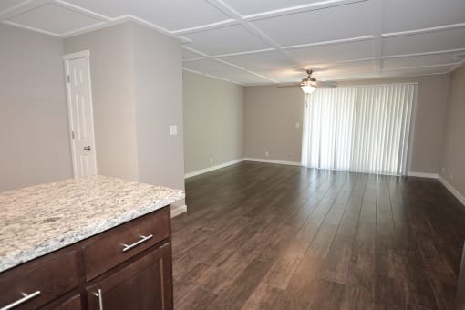 view of living room from kitchen with wood look flooring, ceiling fan, and private patio/balcony access through sliding glass door