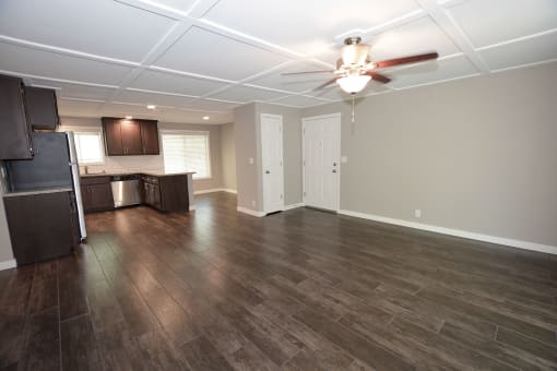 View from living room to kitchen with wood look flooring, stainless appliances, brown cabinets, and ceiling fan