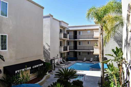 Elevated view from inside the property with entrance to fitness center, community pool, and tropical landscaping