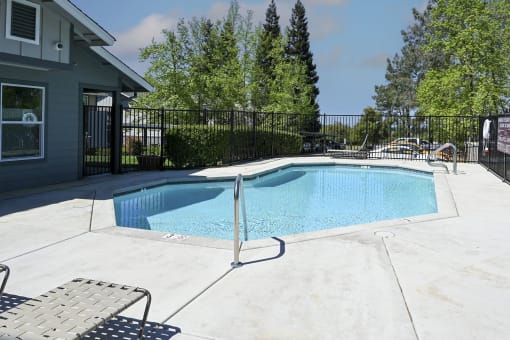 a pool with a fence around it and a house in the background