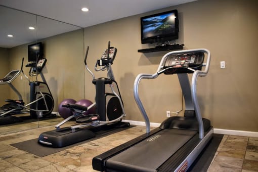 View of gym with treadmill, elliptical, and TV