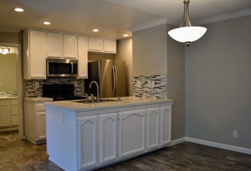 View of kitchen with recessed lighting, stainless appliances, tile backsplash and white cabinets