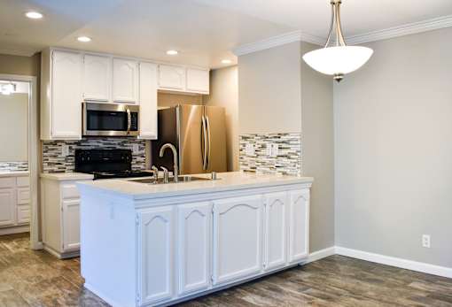 A kitchen with white cabinets and a wooden floor.