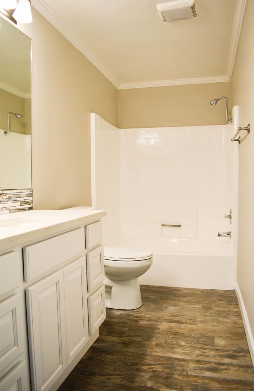 View of bathroom with wood look flooring vanity space and cabinets, white toilet, and white tub shower combo