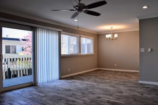 View of living area with wood like flooring, patio  door leading to patio, well lit windows, and veiling fan