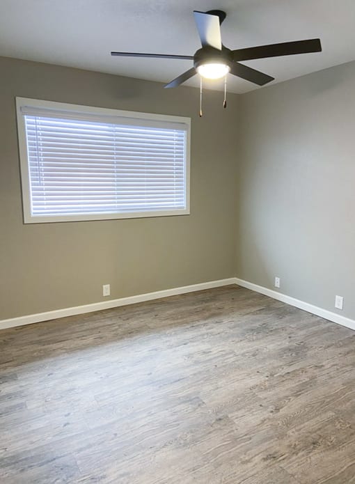 living area with wood look flooring, well lit window, and ceiling fan