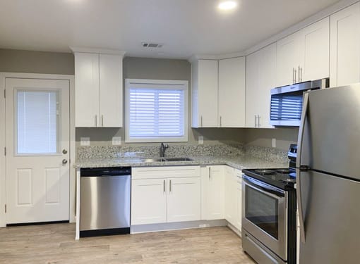 kitchen with stone counters, stainless appliances, white cabinets, recessed lighting and wood look flooring