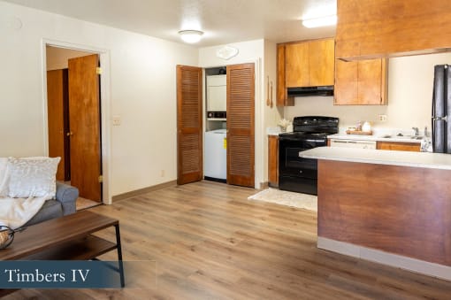 an empty living room and kitchen with wood floors and wooden cabinets