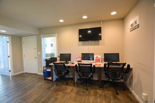 a computer room with desks and chairs and a television