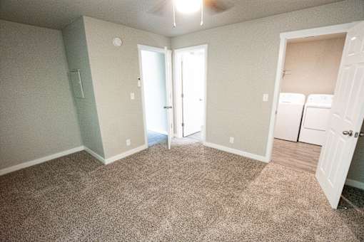 an empty living room with carpet and laundry room