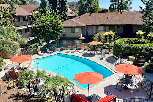 a swimming pool with umbrellas in front of a house