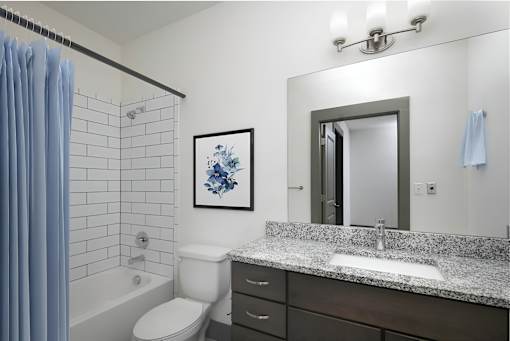 A bathroom with a white toilet, a sink, a mirror, and a blue shower curtain.