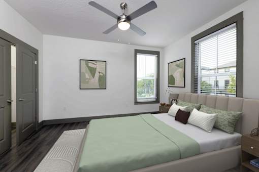 A bedroom with a bed, a ceiling fan, and two pictures on the wall.