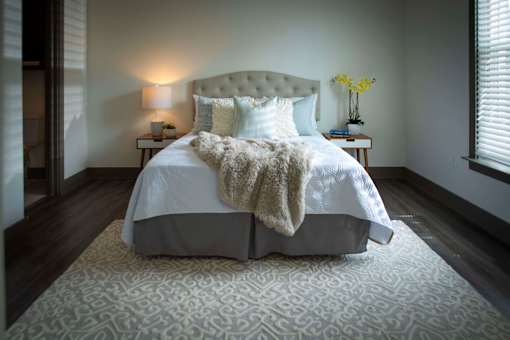 A bed with a white comforter and a white pillow is covered with a white blanket.