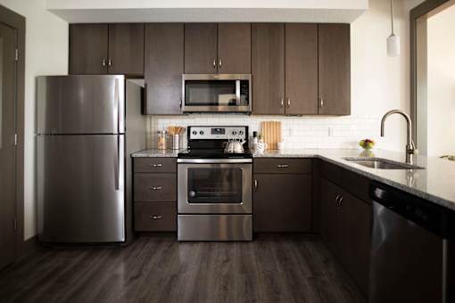 A modern kitchen with a stainless steel refrigerator, oven, and sink.