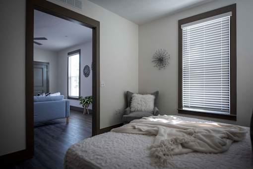 A bedroom with a bed covered in a white blanket and a mirror on the wall.