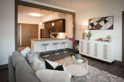 A modern living room with a grey sofa and a glass coffee table.