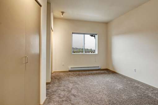 A room with a window and a carpeted floor.