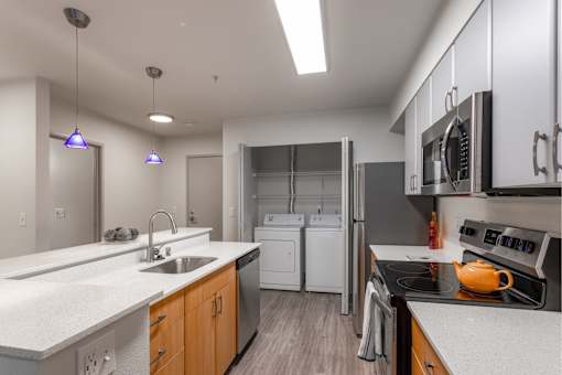 A modern kitchen with a white countertop and stainless steel appliances.