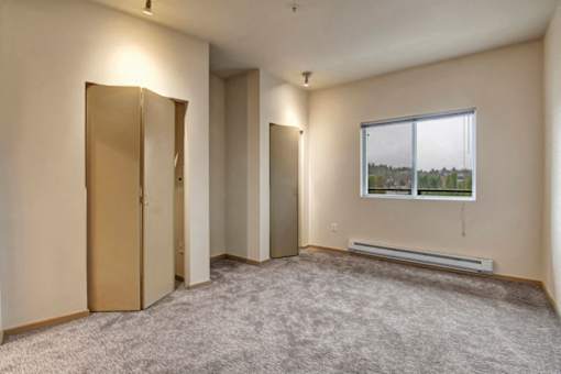 A room with a carpeted floor, a window, and a radiator.