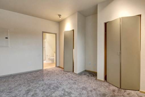 A room with a carpeted floor and three closed doors.