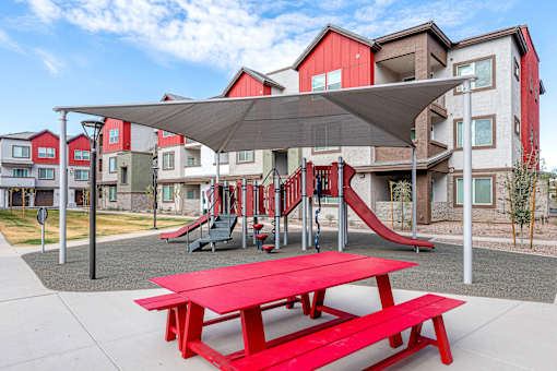 A playground with a red picnic table and slide.