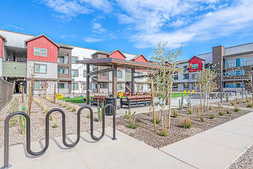 A playground area with a slide and a railing in front of apartment buildings.