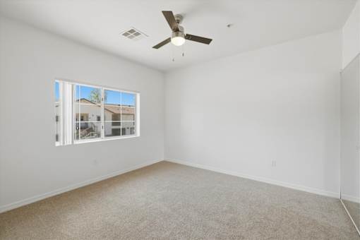 Empty room with a ceiling fan and a window.